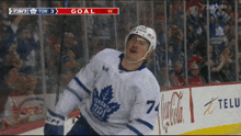 a hockey player in a toronto maple leafs jersey is celebrating a goal