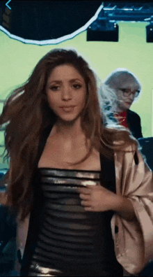 a woman in a black and silver dress stands in front of a green screen