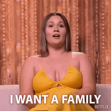 a woman in a yellow dress is sitting on a couch and says i want a family