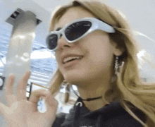 a woman wearing sunglasses is smiling and giving a thumbs up .