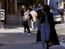 a woman walking down a sidewalk in front of a pay phone