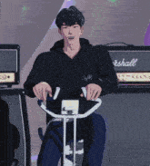 a man in a black marshall hoodie rides an exercise bike