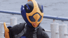 a person wearing a blue and yellow costume is standing next to a railing .