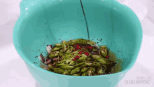a blue bowl filled with green peppers and red peppers is being made in animatica