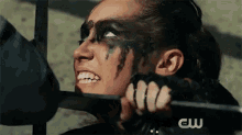 a woman with black paint on her face is holding a metal bar in her hand .