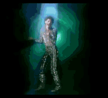 a man singing into a microphone in a dark room with a green light behind him
