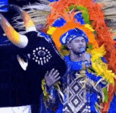 a man in a colorful costume is singing into a microphone next to a bull mask