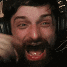 a man with a beard is wearing headphones and making a face
