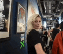 a woman in a black shirt is standing in a hallway next to a poster that says " you your "