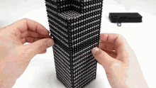 a person is holding a black and silver cube that looks like a building