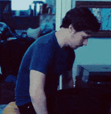 a man in a blue shirt is kneeling down in a room