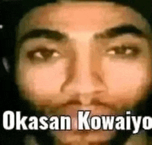 a close up of a man 's face with a beard and the words okasan kowaiyo written on it .