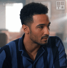 a man with a beard is wearing a blue and black striped shirt with the words sistas on the bottom