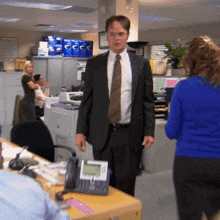 a man in a suit and tie stands in front of a phone