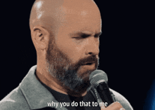 a bald man with a beard is holding a microphone and saying why you do that to me