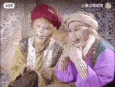 a man in a turban is talking to another man in a purple shirt