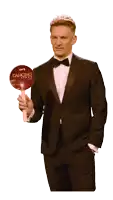a man in a tuxedo holds a dancing with the stars sign