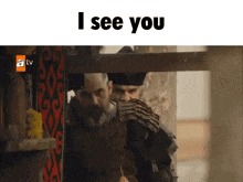 a man with a beard is standing in front of a sign that says ' i see you '