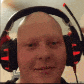 a bald man wearing red and black headphones with a red microphone