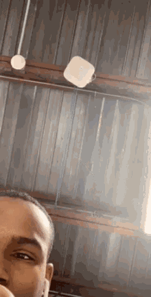 a man is taking a selfie in front of a metal wall with a white object hanging from the ceiling .