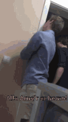 a man in a blue shirt is standing in front of a door with the words " alle arme er home " on the bottom right