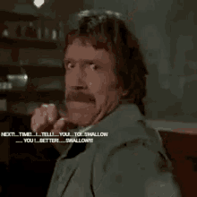 a man with a beard and mustache is making a funny face while talking to another man .