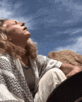 a woman sitting on a rock with her eyes closed and her mouth open