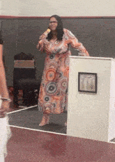 a woman in a colorful dress stands in front of a podium