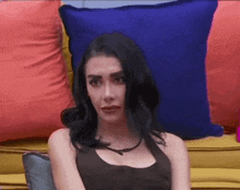 a woman is sitting on a couch with a lot of pillows .