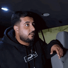 a man with a beard is wearing a black hoodie with the word power on it