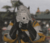a person wearing a yellow and black jacket is holding a white camera