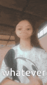 a girl in a mickey mouse shirt is making a funny face and says whatever .
