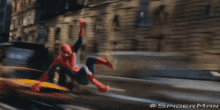 a spider man is hanging from a rope in front of a building .