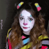 a woman is wearing a clown costume and making a sad face .