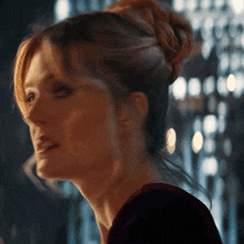 a close up of a woman 's face with a bun on her head