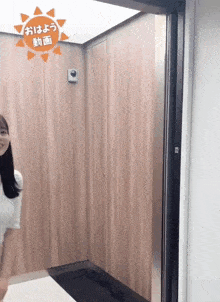 a woman stands in an elevator with a sun sticker on the wall above her