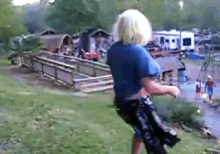 a little girl in a blue shirt and black shorts is jumping in the air