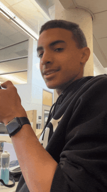a young man wearing a black nike sweatshirt looks at the camera