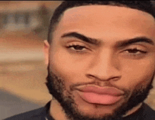 a man with a beard is making a funny face with his mouth open and his eyes closed .