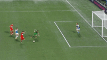 a soccer game is underway and a goalie is diving to catch a ball