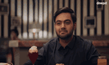 a man sitting at a table with a glass of wine in front of him and the word dineout on the bottom right
