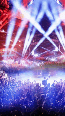 a crowd of people at a concert with blue and red lights coming from the stage