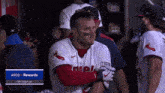a baseball player is hugging another player in a dugout with a sign that says arco rewards top tier play