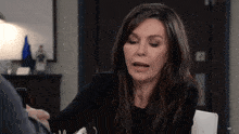 a woman in a black shirt sits at a table with a man