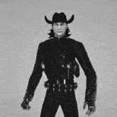 a black and white photo of a man in a cowboy hat holding guns