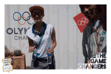 a woman stands in front of a sign that says olympics