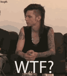 a man with a mohawk is sitting on a couch with the words wtf written on it