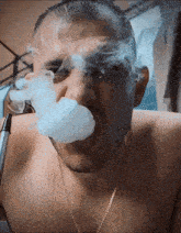 a shirtless man smoking a hookah with smoke coming out of his nose