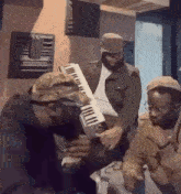a group of men are sitting around a piano in a room .