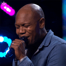 a man singing into a microphone with a pink star on the bottom right